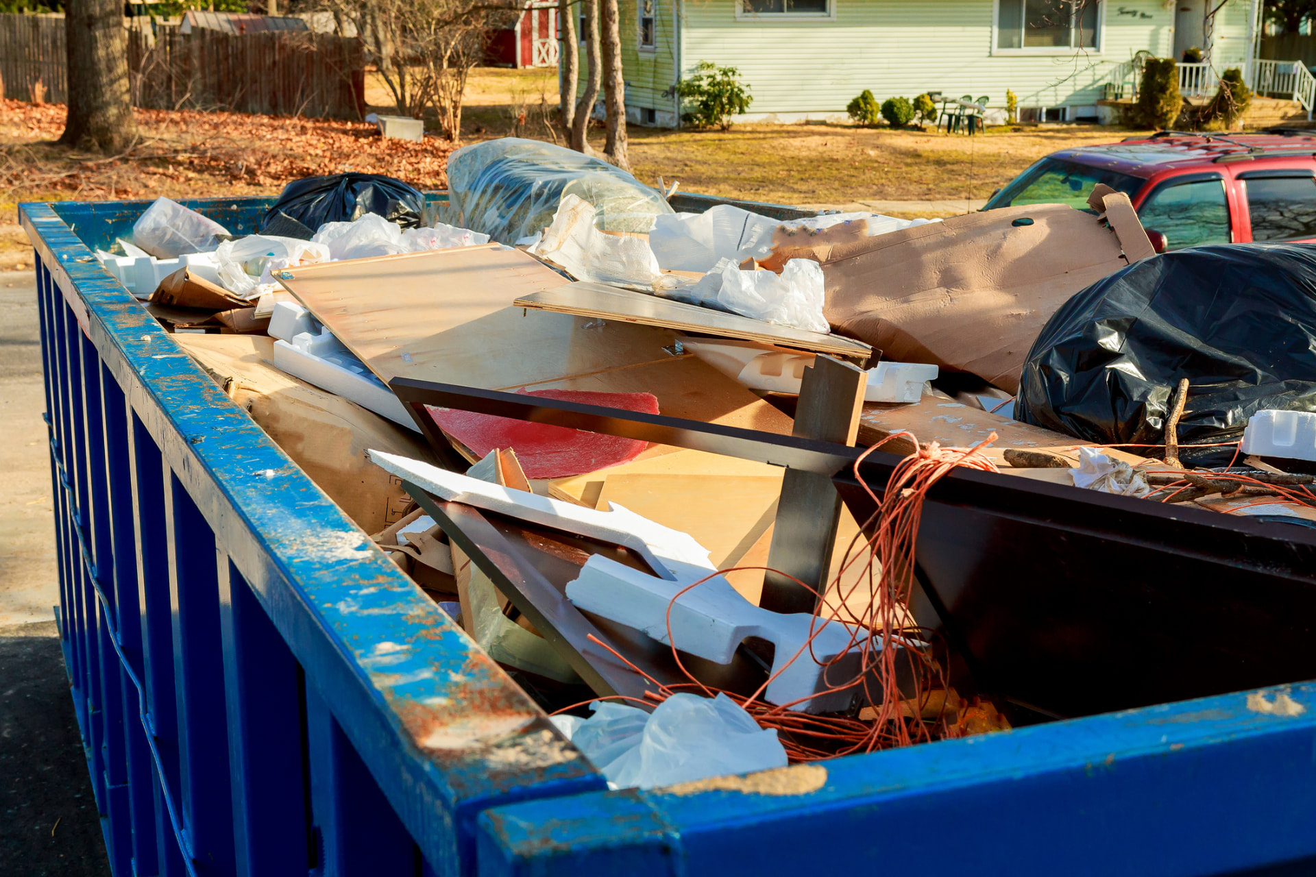 Dumpster filled with household junk and packaging outside a residential home
