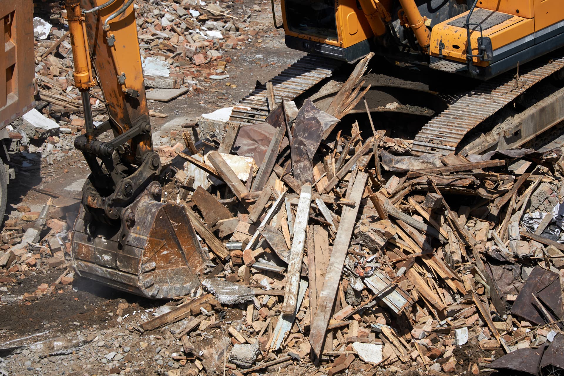 Excavator loading construction debris and scrap wood during a demolition cleanout