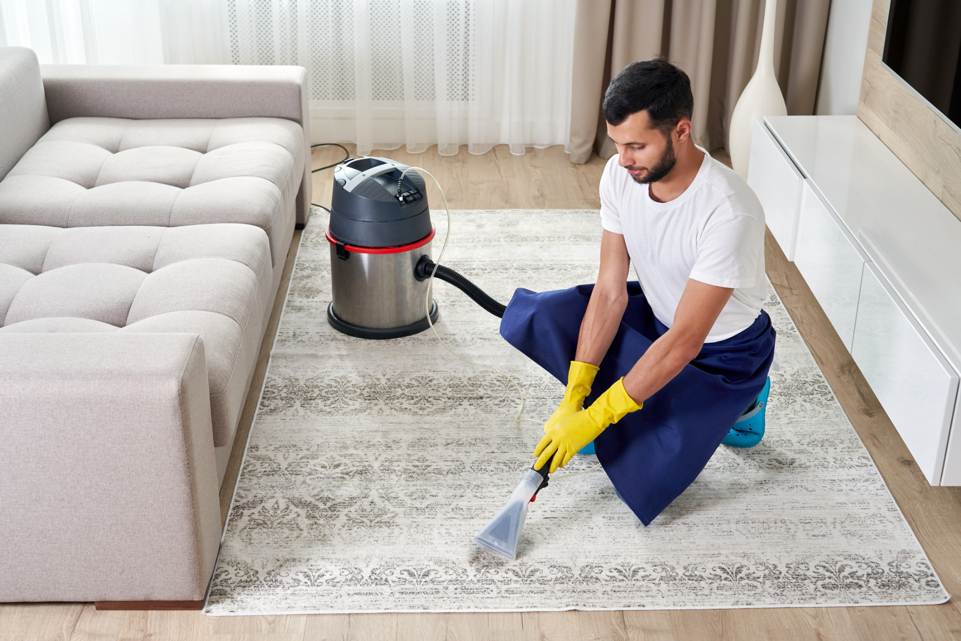 Technician deep-cleaning a living room area rug with an extraction machine