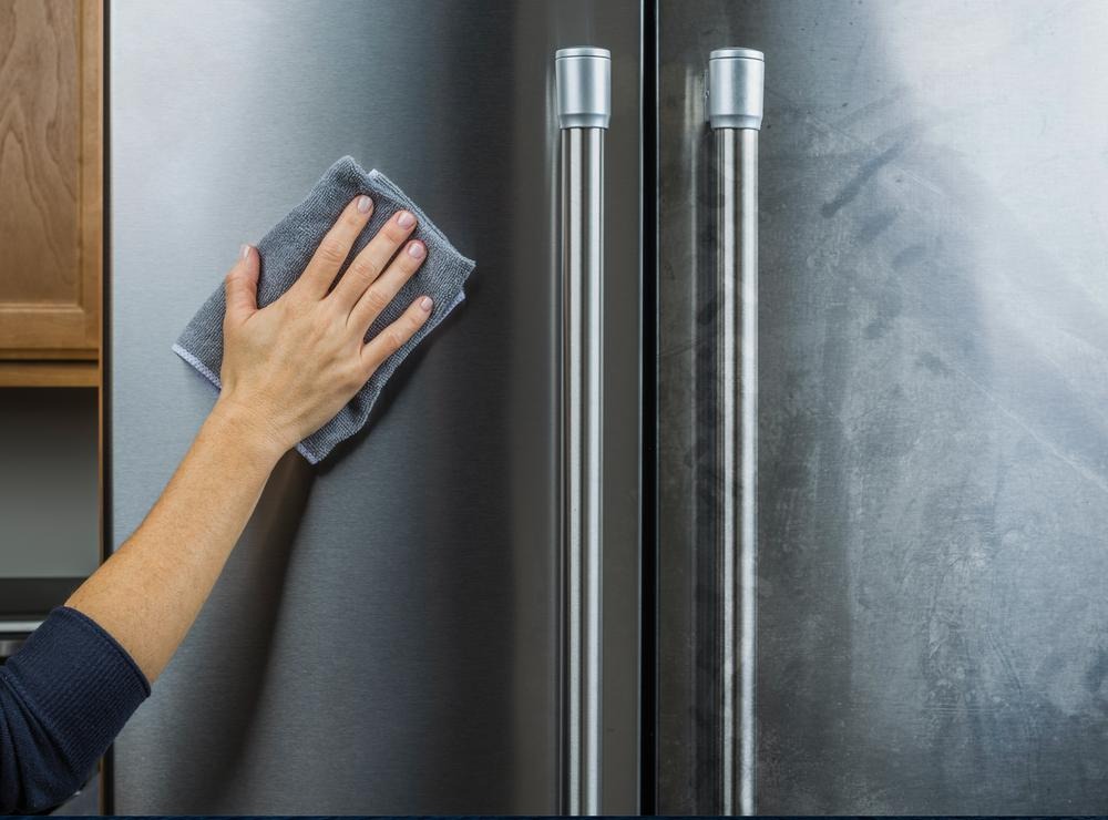 Cleaner polishing a stainless steel refrigerator during an interior cleaning in Kent, Ohio