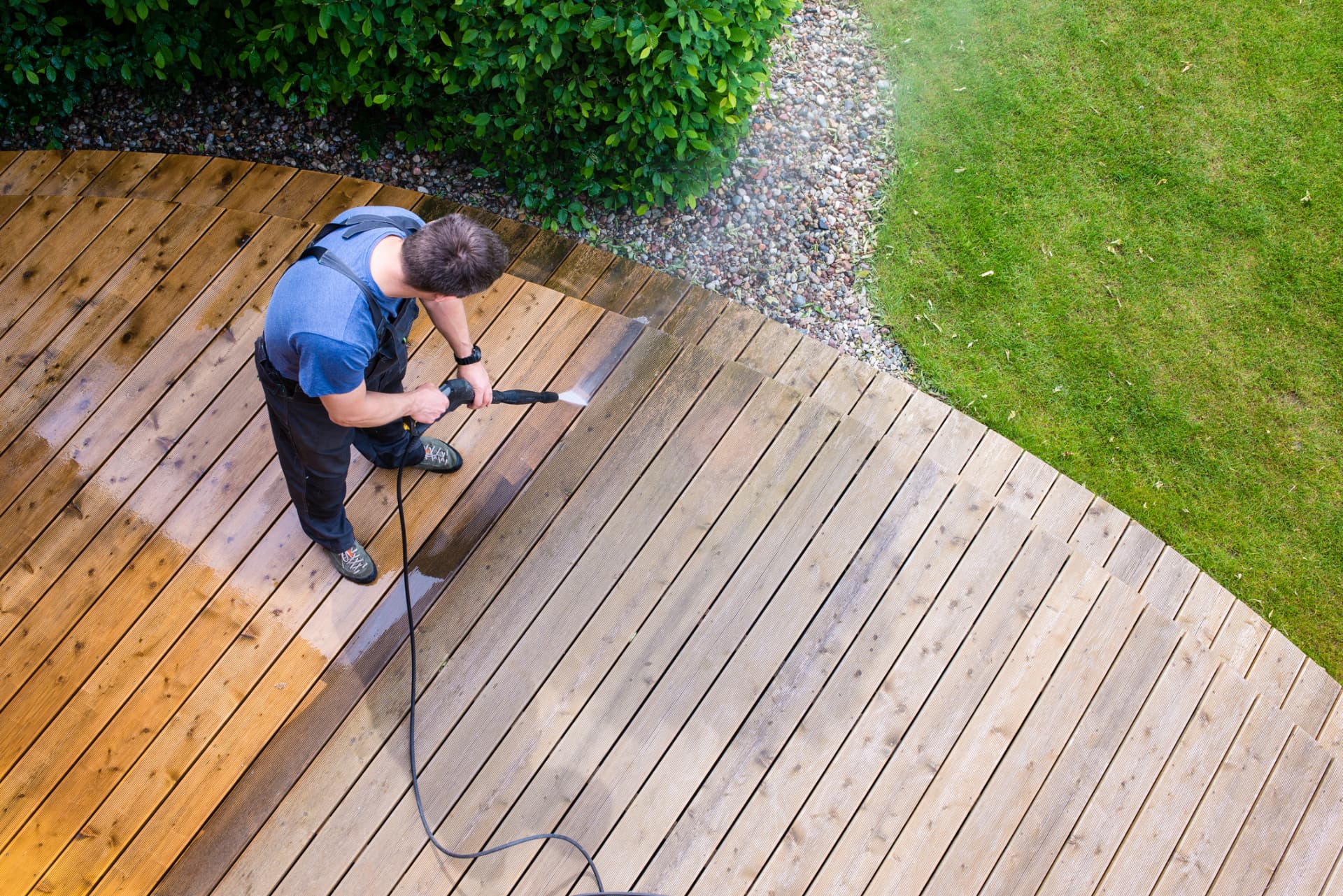 Technician pressure washing a wooden backyard deck in Alliance, Ohio
