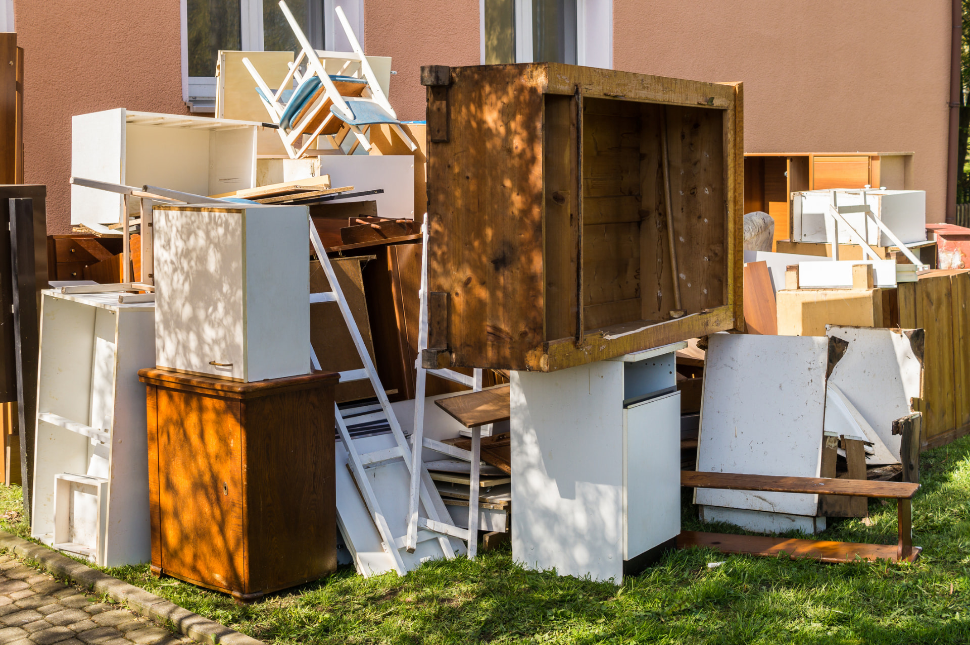 Old cabinets, chairs and furniture piled outside a home ready for junk removal