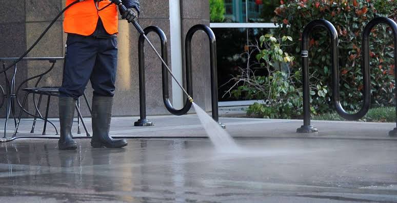 Technician pressure washing a commercial sidewalk in Alliance, Ohio