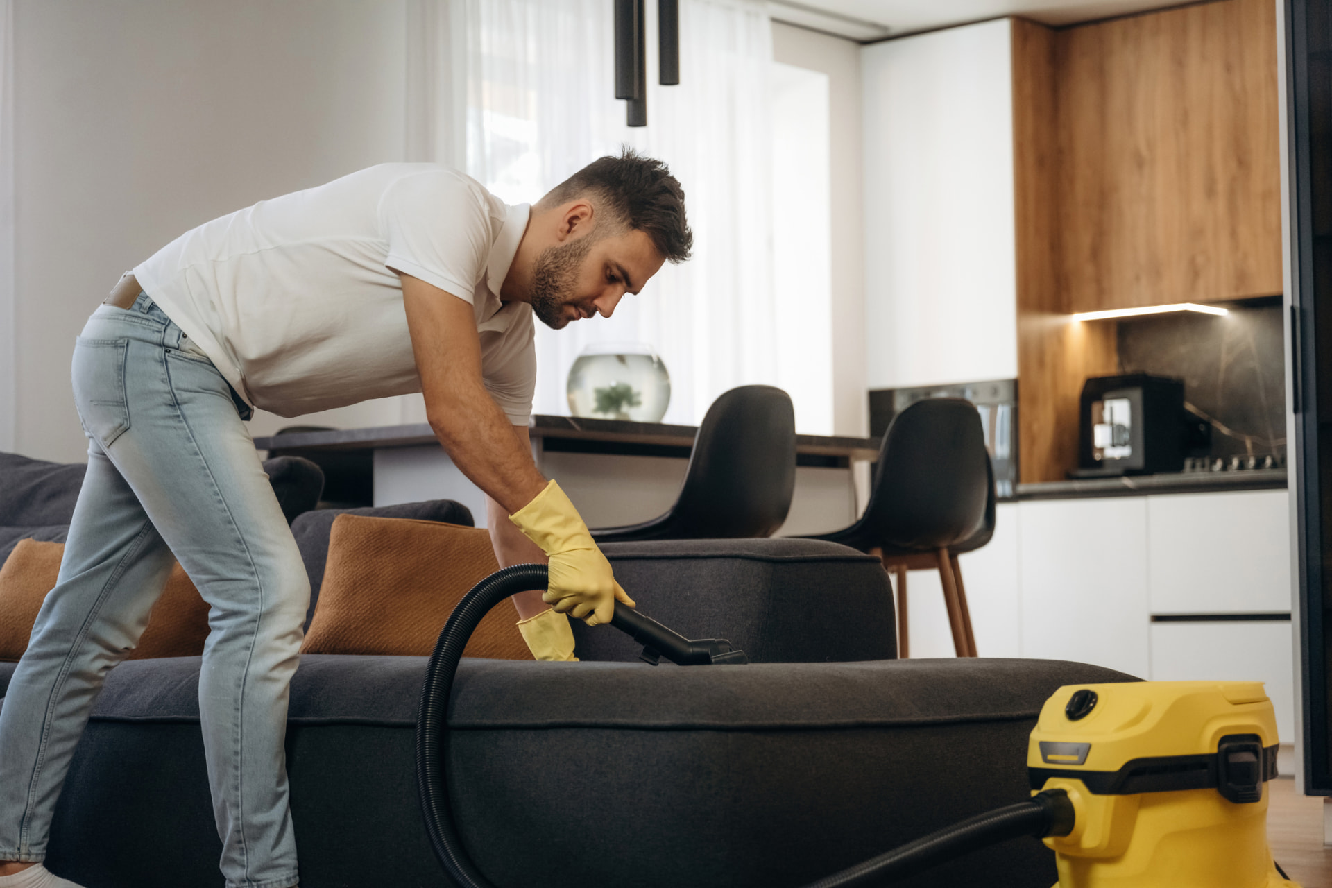 AllClear technician vacuuming an upholstered sofa during an interior cleaning in Alliance, Ohio
