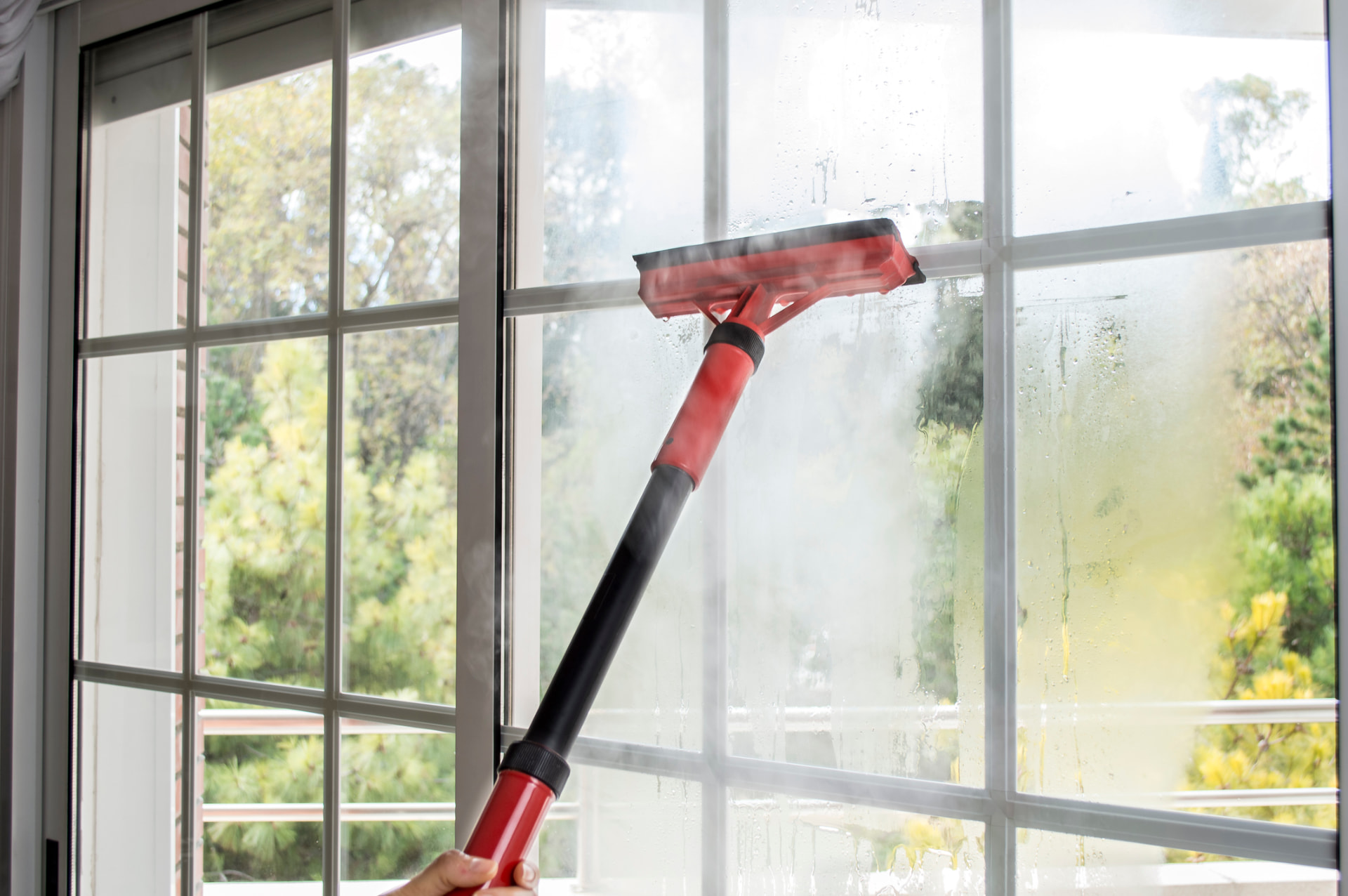Steam-cleaning interior window glass during an AllClear interior cleaning in Alliance, Ohio