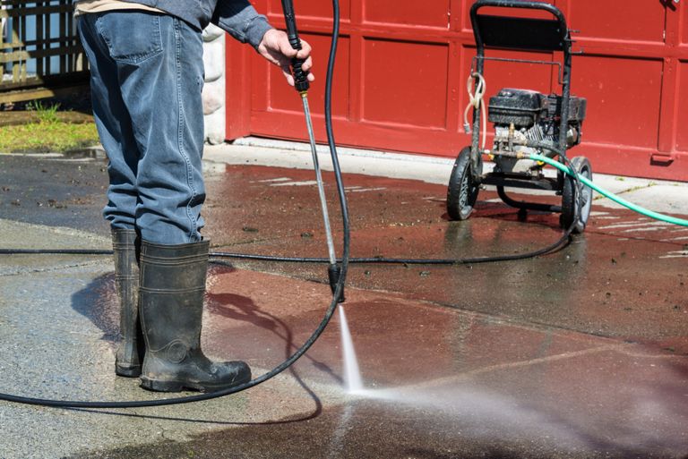 Pressure washing a concrete driveway outside a garage in Chagrin Falls, Ohio