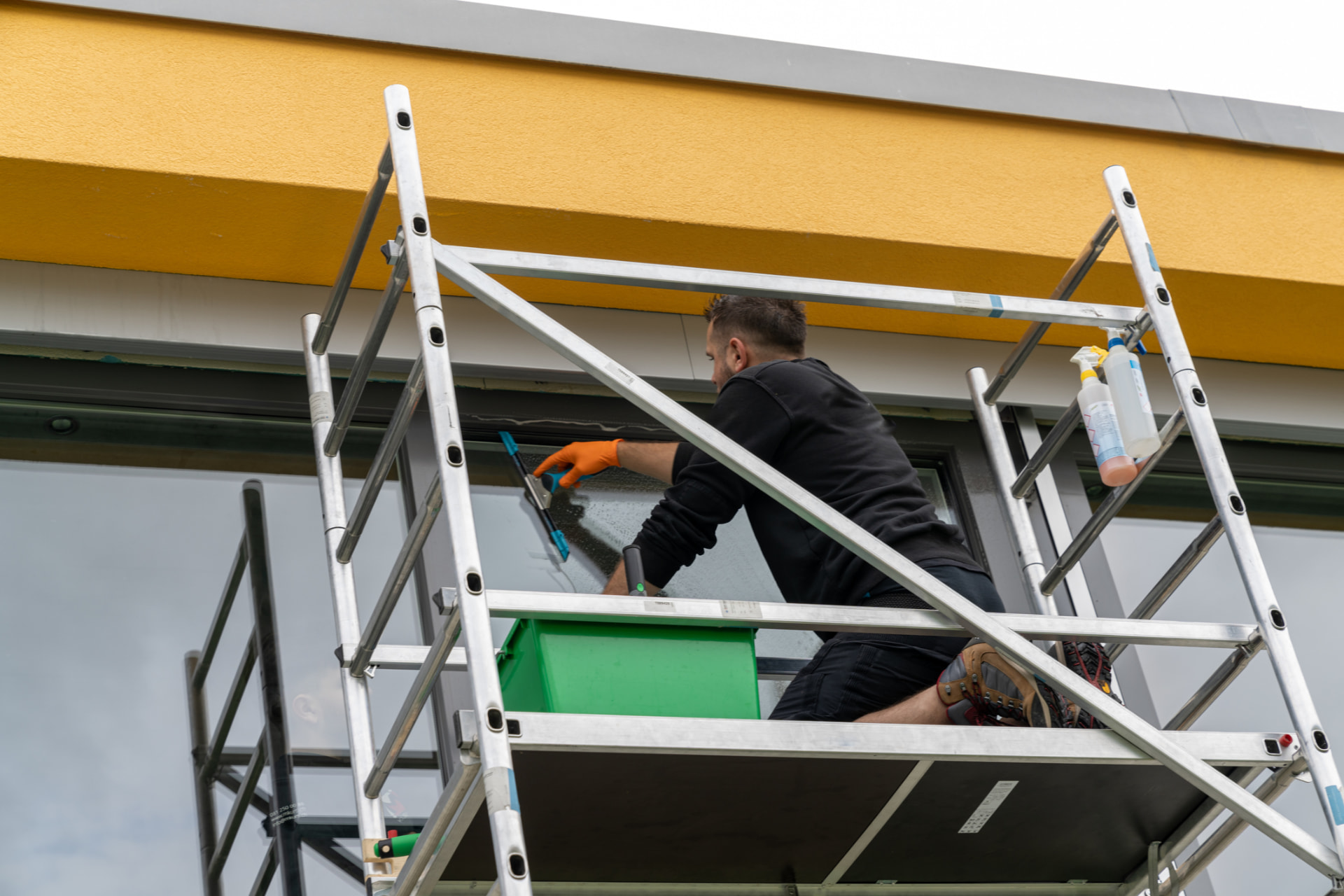 AllClear technician squeegeeing a commercial window from scaffolding