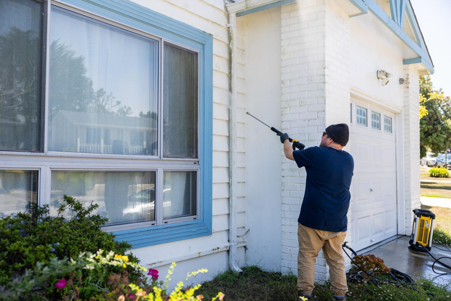 Technician soft washing painted siding and brick trim on a ranch home in Alliance, Ohio