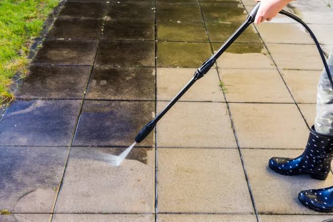 Technician rinsing a stained concrete driveway with a pressure washer in Chagrin Falls, Ohio